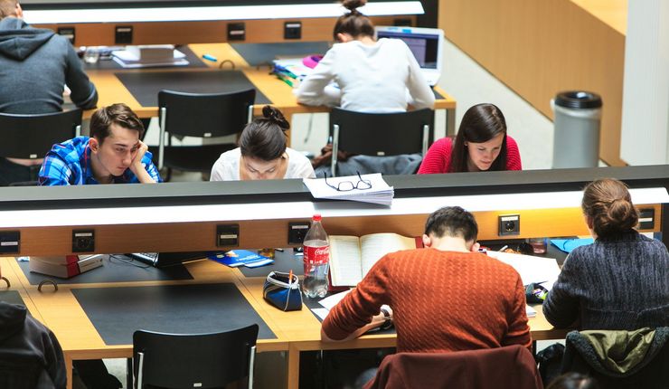 Foto: Studierende sitzen an Schreibtischen in der Bibliothek und arbeiten